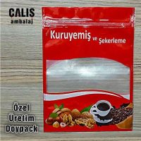 Kırmızı doypack ambalajında kuruyemiş ve şekerleme, şeffaf pencere ile içeriği gösteren, çeşitli kuruyemişler, kahve fincanı ve şekerlemelerle süslenmiş.